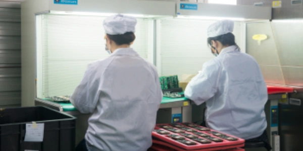 Operators perform visual inspection and hand rework of PCBAs at ESD-safe benches as part of SMT quality control.