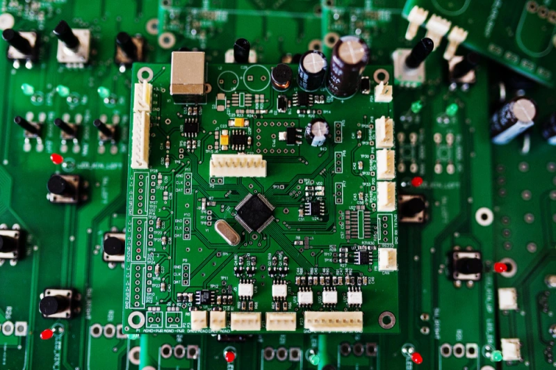 Fully assembled printed circuit board (PCB) with microchips, capacitors, and connectors for electronic devices.