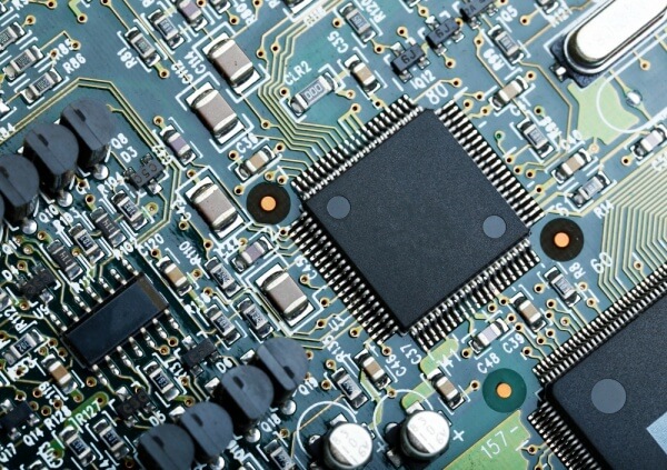 Close-up of a printed circuit board (PCB) with surface-mounted IC chips, capacitors, and other components.