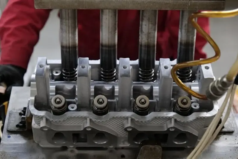 Alt: Industrial Internet of Things view of high-precision stamping on an engine cylinder head in a manufacturing line.