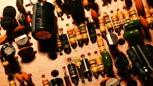 Close-up of electronic components on a PCB, including resistors and capacitors, demonstrating how resistors work in real circuits.