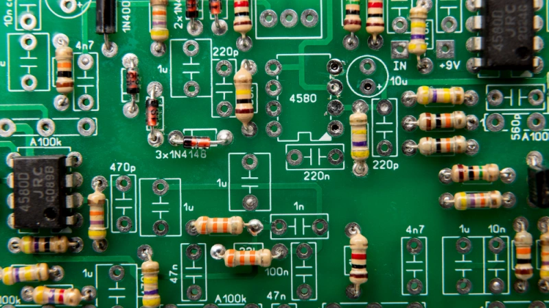 Green printed circuit board with multiple 10k resistors and integrated circuits soldered in a modern electronic assembly.