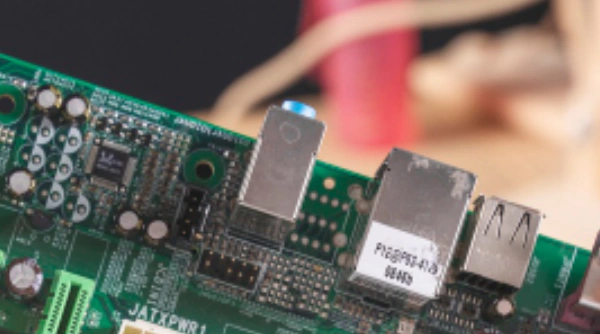 Close-up of a green printed circuit board (PCB) featuring prominent PCB switches, various electronic components including chips and resistors, and integrated USB ports.