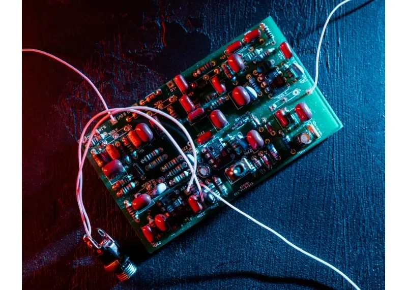 Assembled PCB with mixed components photographed under red and blue lighting to illustrate complex circuit layouts