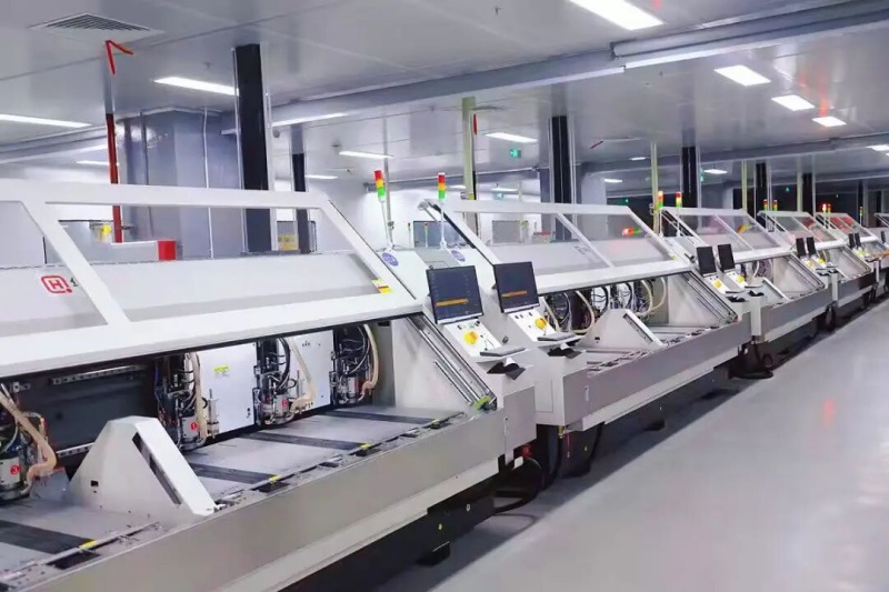 Row of modern multi-spindle CNC drilling machines on a clean PCB manufacturing factory floor, highlighting automated high-volume production capabilities.