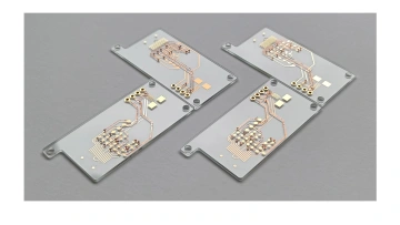 Four rigid transparent PCB boards on a gray background showing visible copper circuit traces