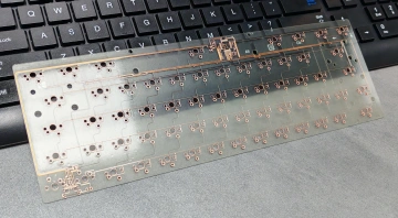 Transparent keyboard PCB with visible circuit traces placed on top of a physical keyboard